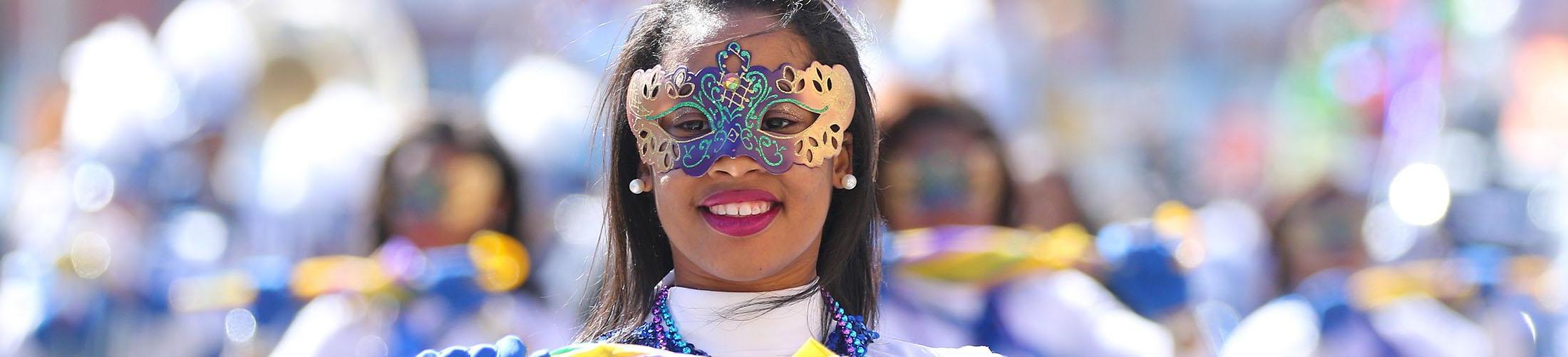 Female in mask marching in mardi gras parade.